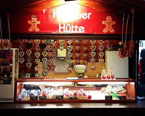 Markthütte mit Lebkuchenherzen zur Weihnachtzeit vor einem Hotel.